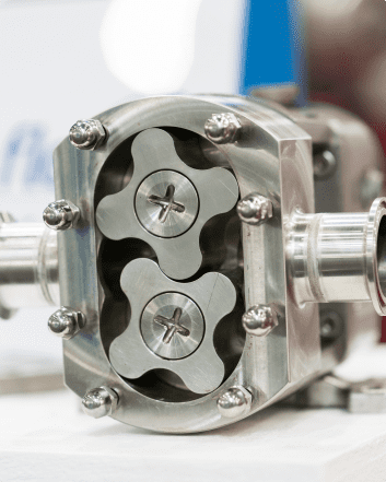 A close-up view of a metal hydraulic pump featuring four valves, highlighting its intricate design and repair details.