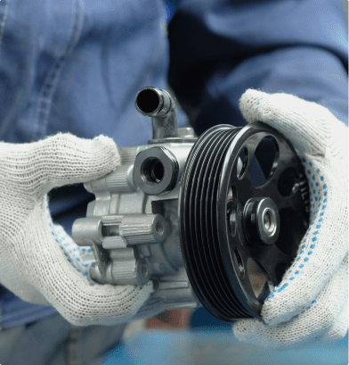 A mechanic holds a small car engine, focused on hydraulic pump repair, showcasing expertise in automotive maintenance.